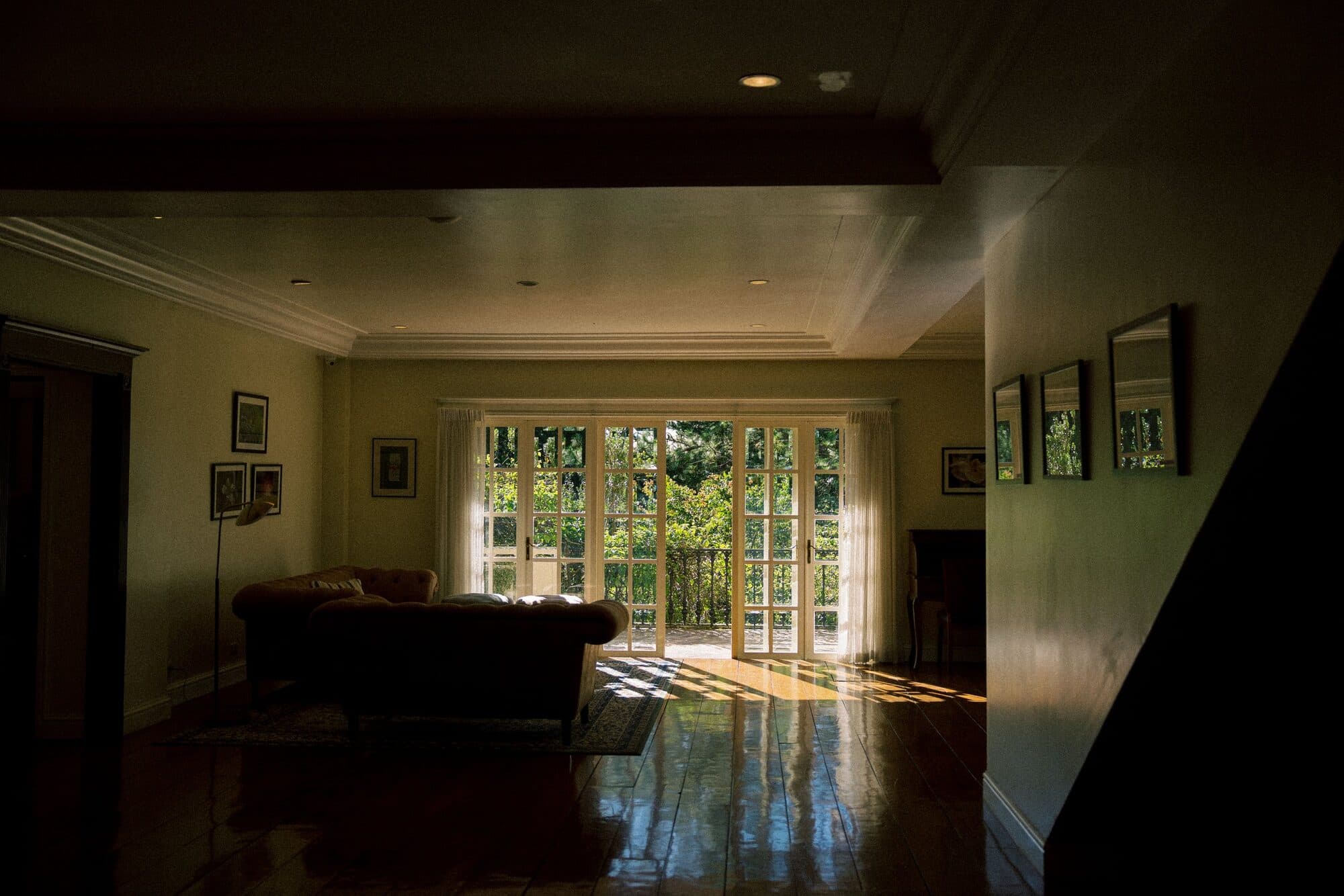 The sunlit living room of Frangeli House, empty and quiet, its garden doors open to the trees