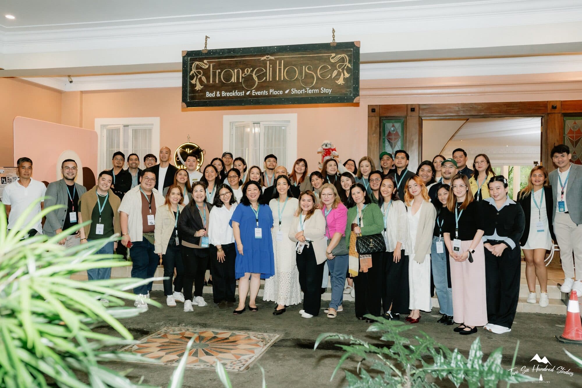 Attendees of WaW Meets Suppliers posing together on the porch under the Frangeli House sign