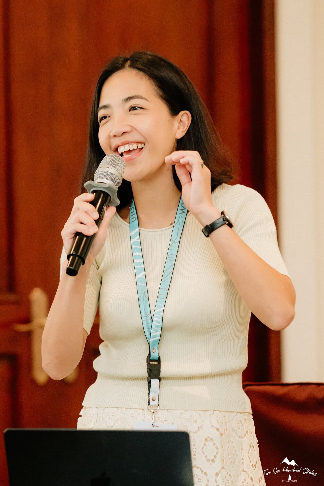 Chaya Claver laughing as she speaks into a microphone beside her laptop