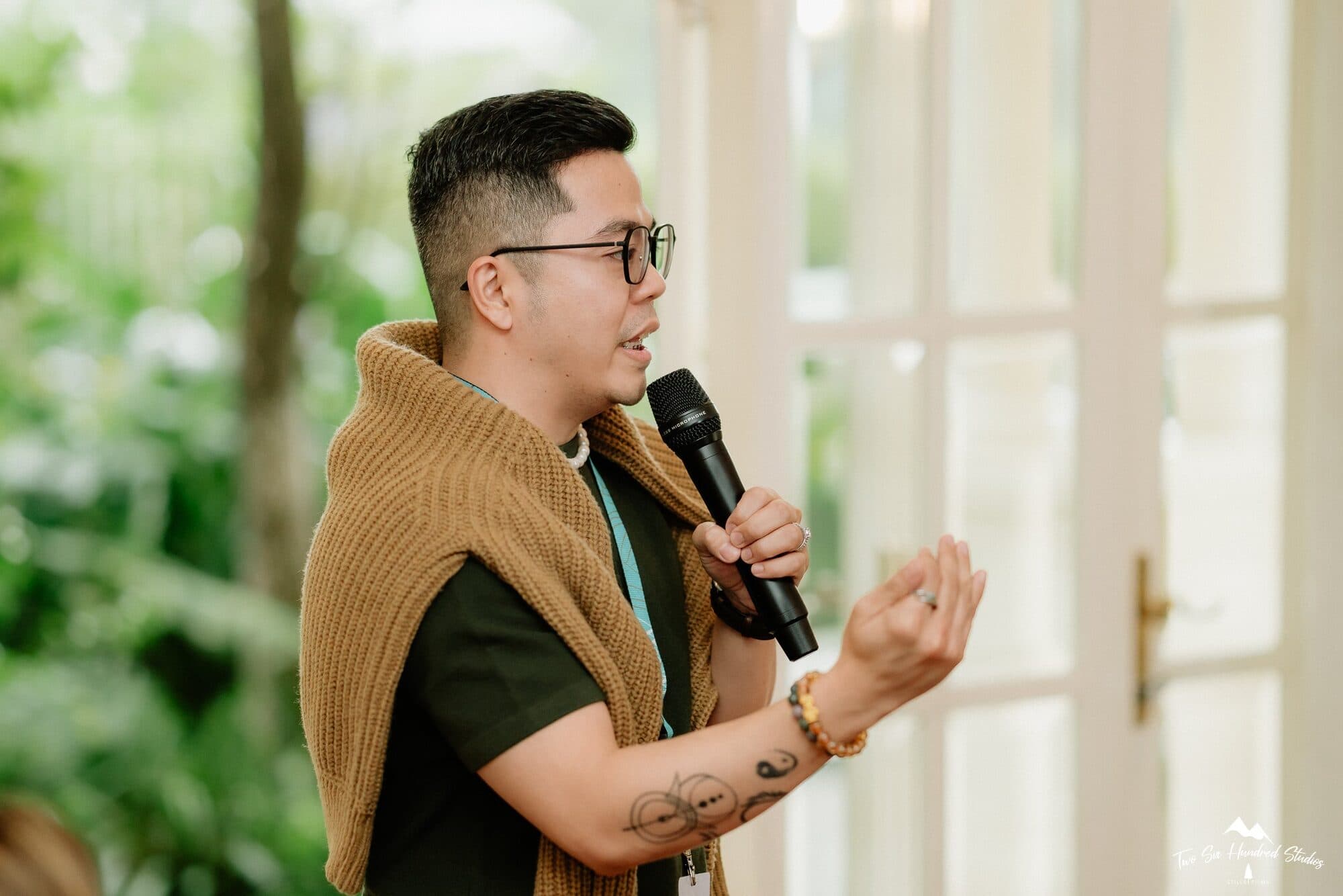 Daday Limjuco speaking into a microphone by the garden windows