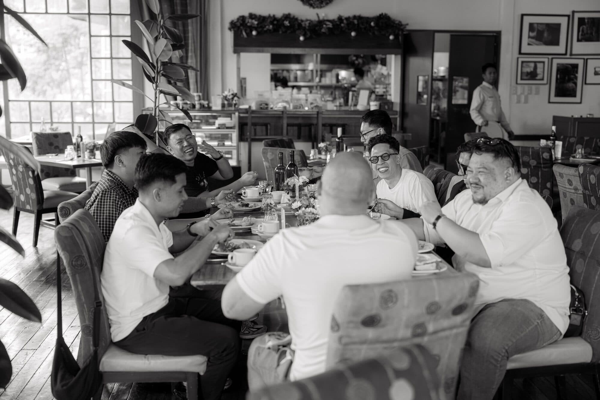The groom having brunch with his friends around a restaurant table, all of them laughing