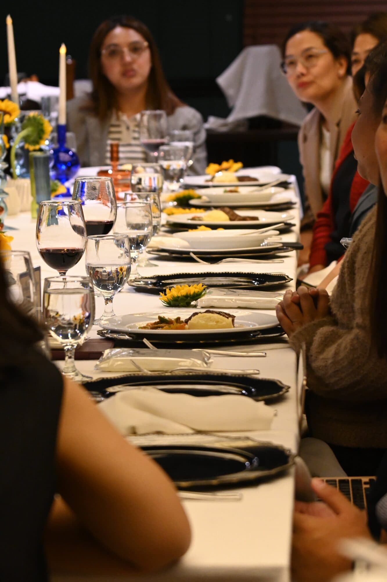A view down the length of the table, plated steak courses, wine glasses and folded napkins in a row