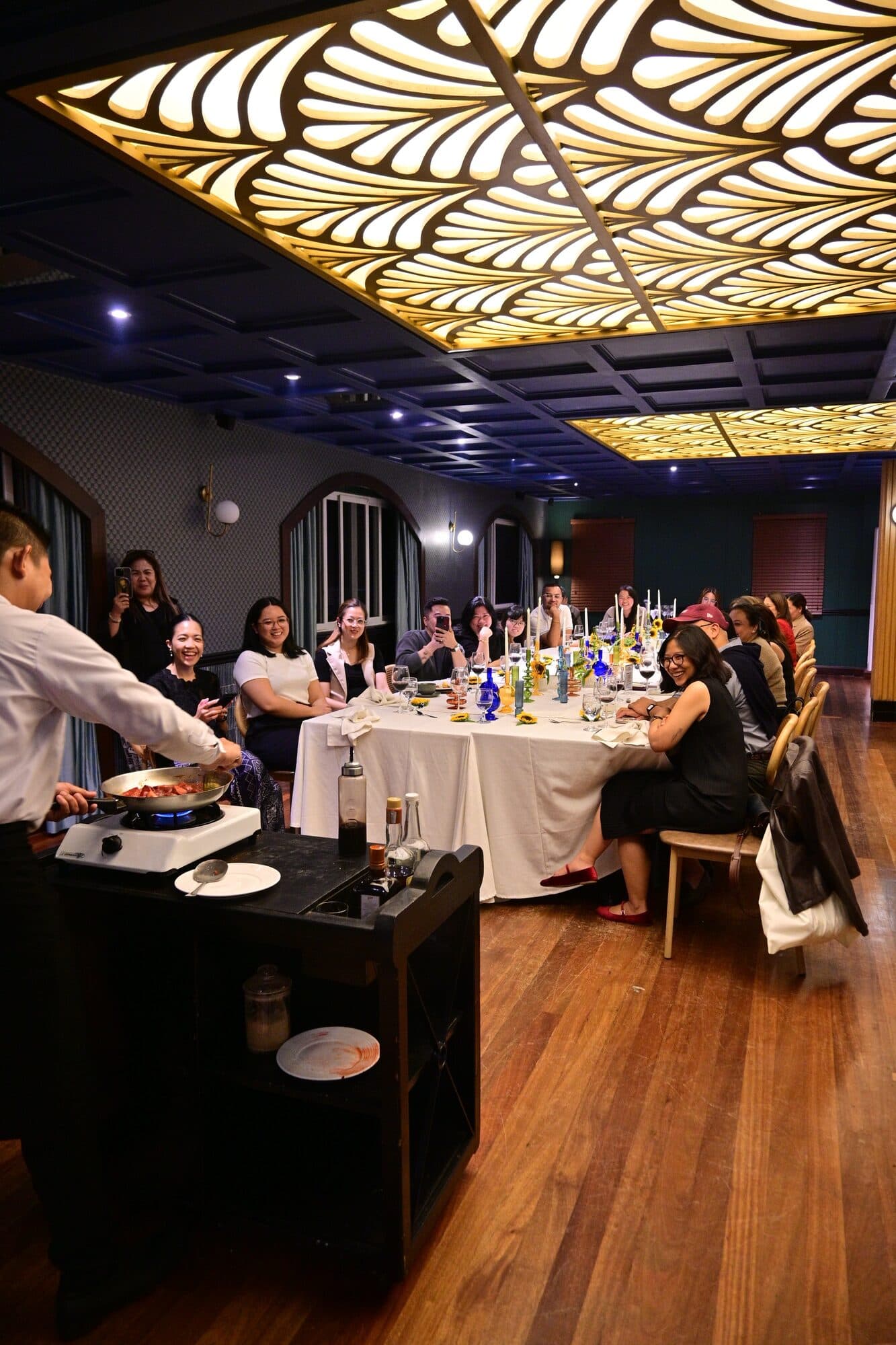 Guests at the long table watching the tableside flambé cart being prepared