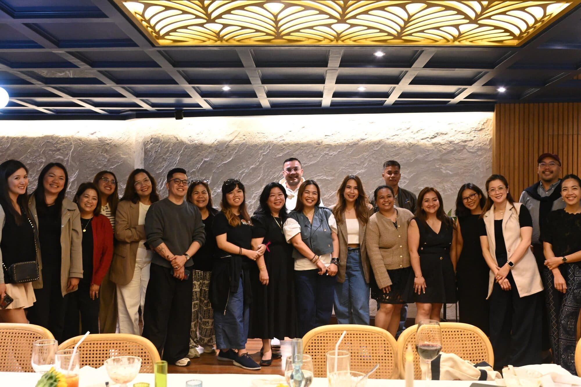 A group portrait of the wedding community standing together inside the restaurant